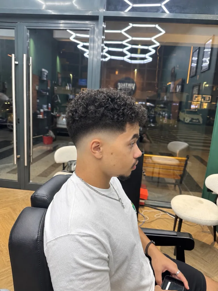 The same curly haircut seen from the other side, showing the faded nape and curl volume