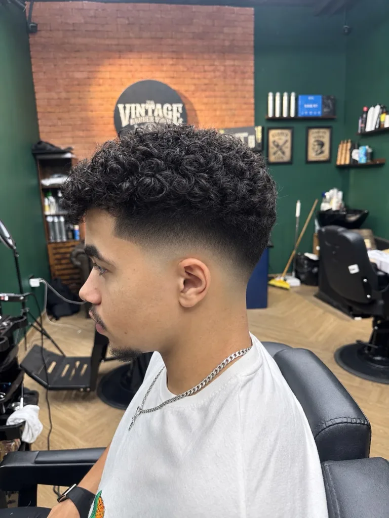 Side view of curly hair left long on top, with short faded sides and a sharp front line-up